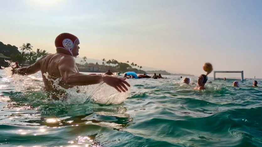 Water polo players in a match in the open ocean at sunset