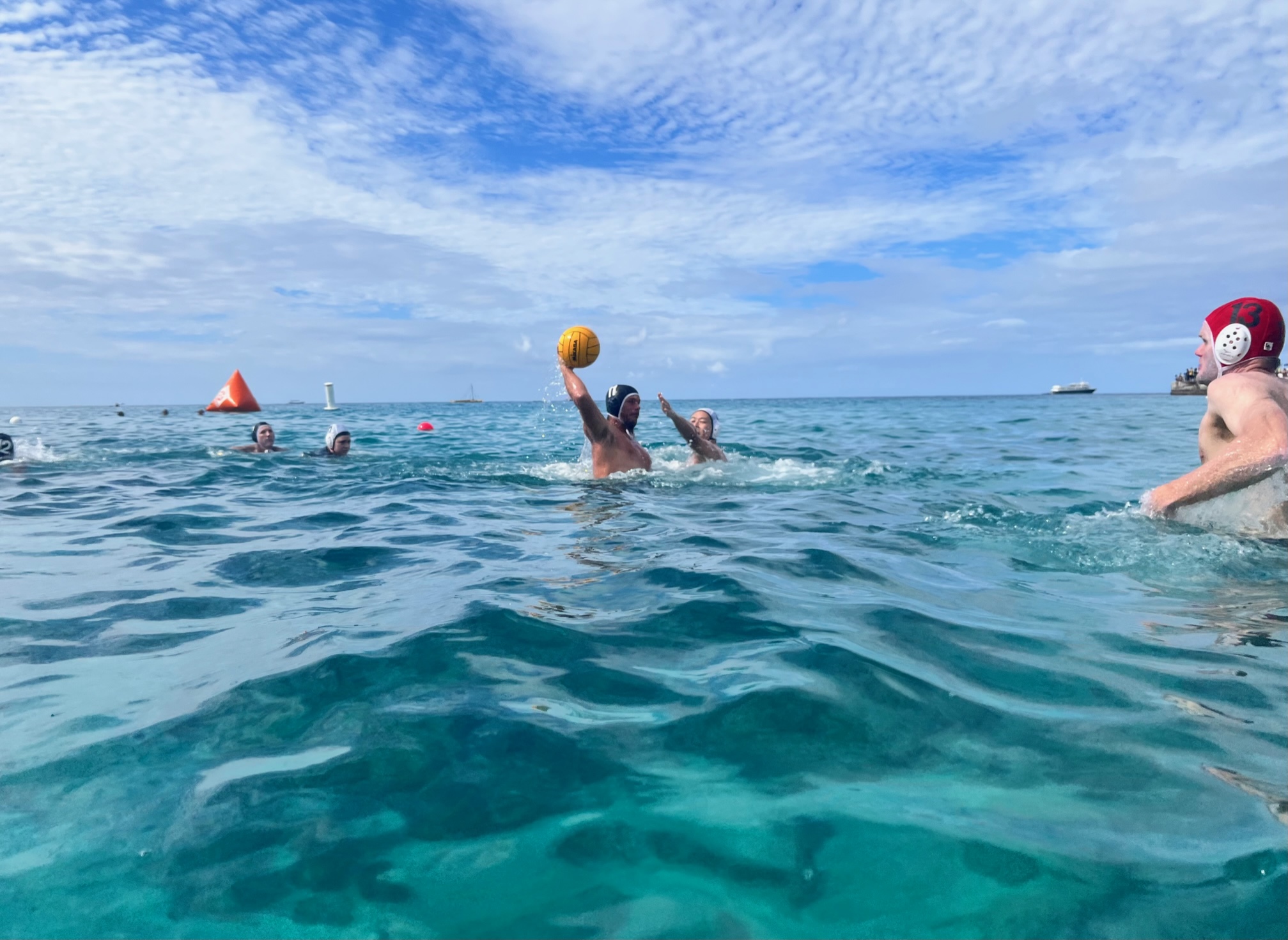 Water polo game action with a player reaching for the ball